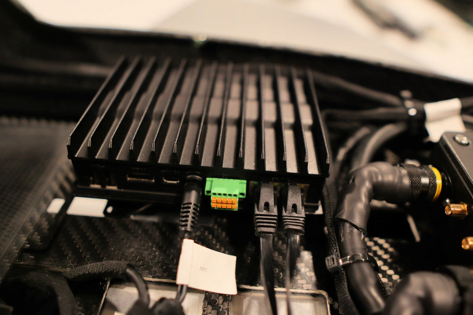 Black finned ARC mission computer installed inside an Avidron Echo aircraft with its power, network, and aircraft-interface cables connected.