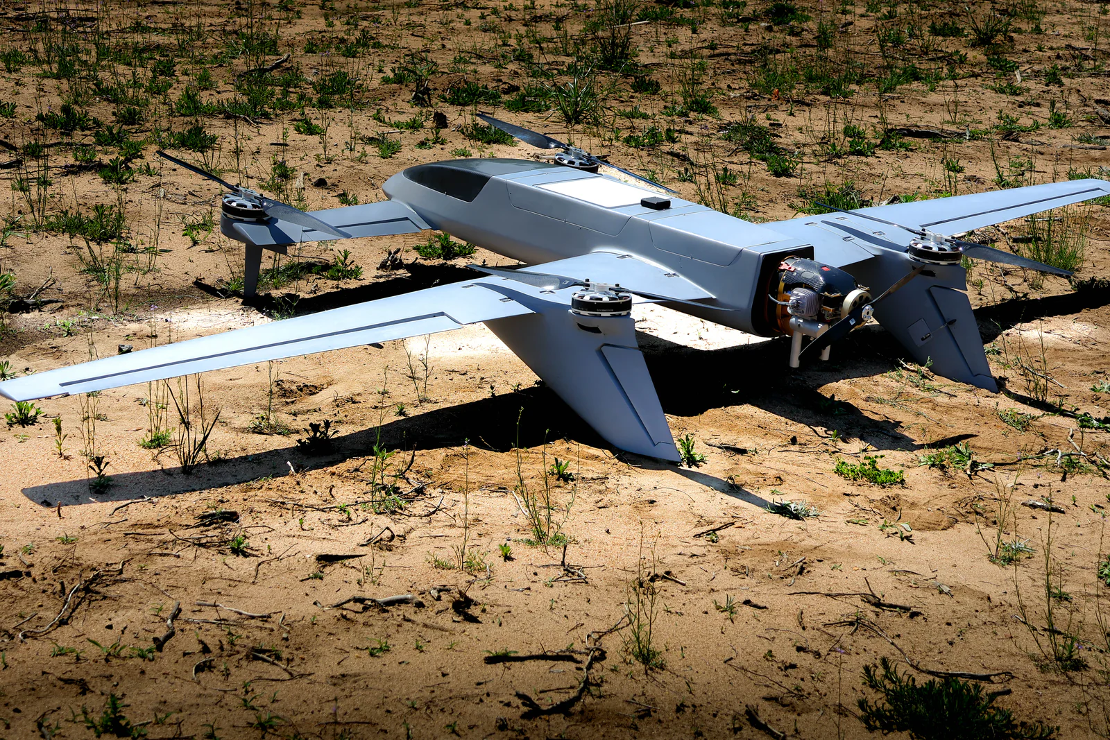 Gray Avidron Echo fixed-wing VTOL aircraft resting on sandy ground with its four lift rotors and rear propeller visible.