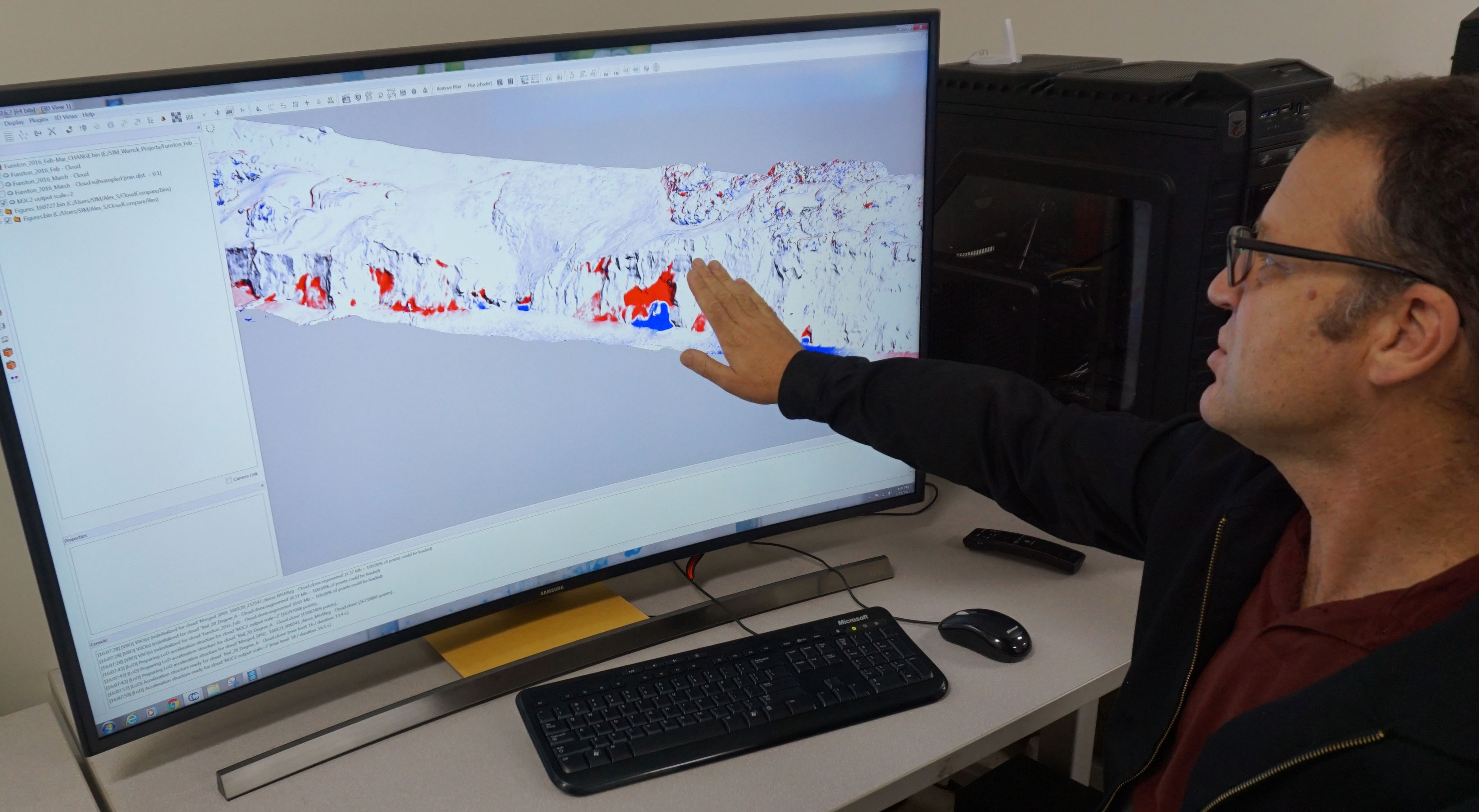 USGS geologist pointing to a three-dimensional coastal change map on a desktop monitor