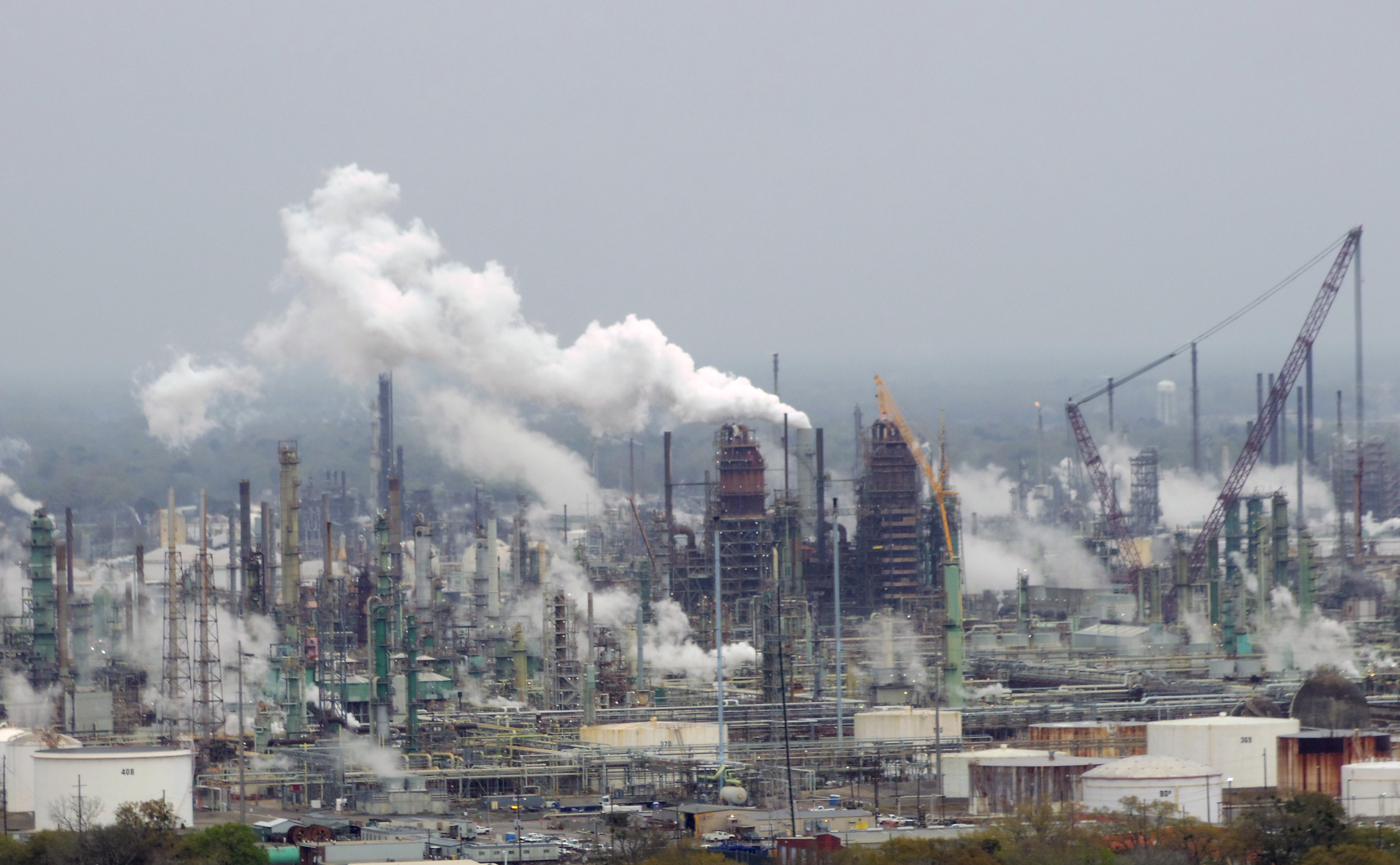 Refinery towers, pipework, storage tanks, and cranes beneath an overcast sky in Baton Rouge.