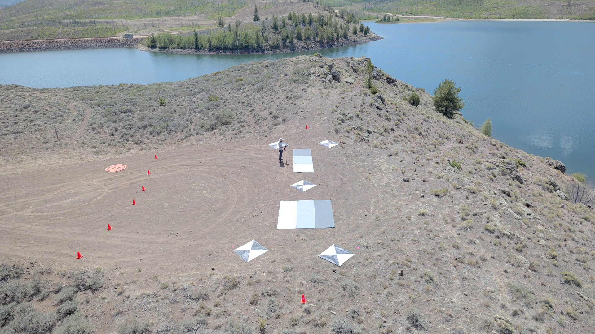 Ground control targets and grayscale tarps arranged beside Willow Creek Reservoir, with a field worker among them