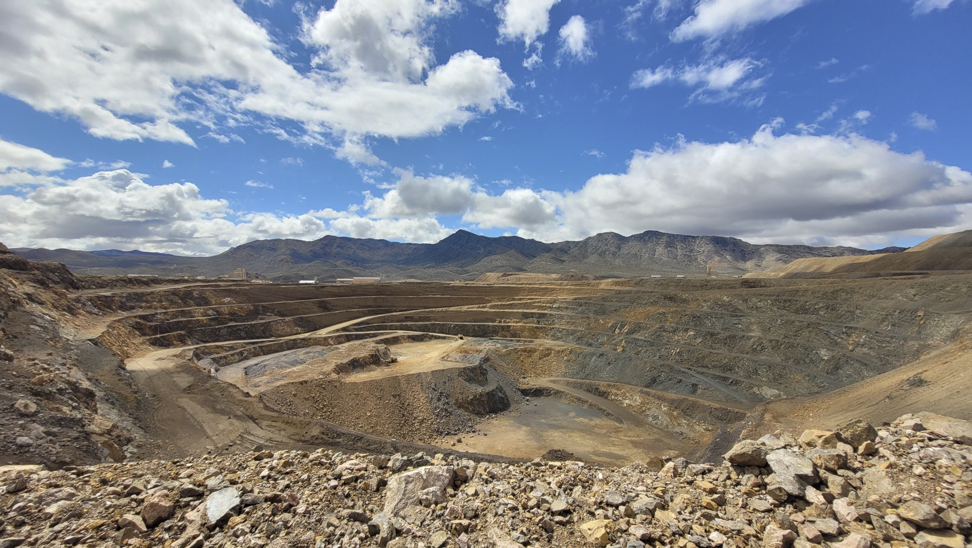Terraced rock faces, benches, and winding vehicle access roads in the open pit at Mountain Pass, California.