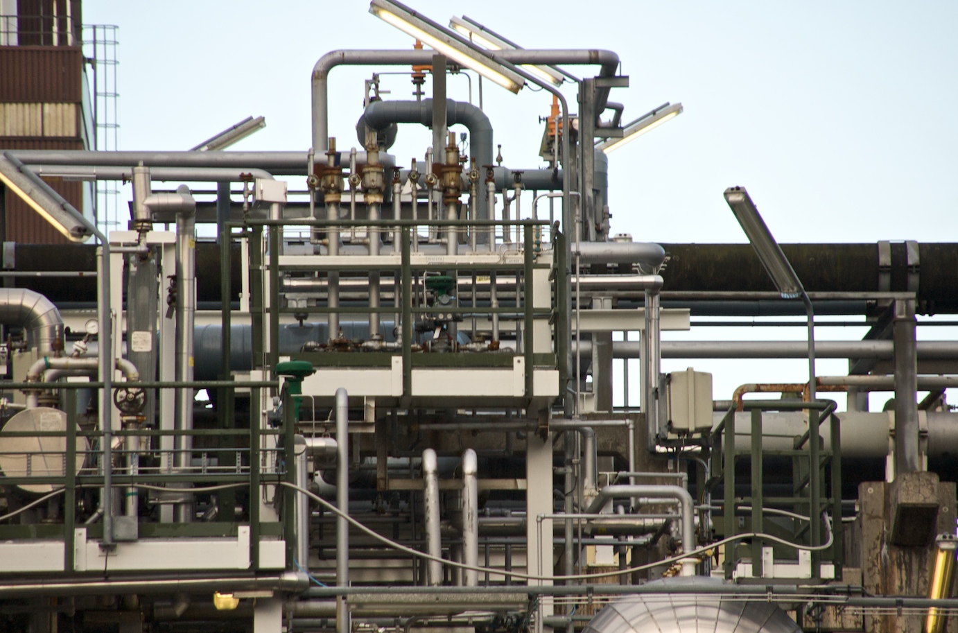 Intersecting pipes, valves, platforms, and steel supports in a petrochemical plant.
