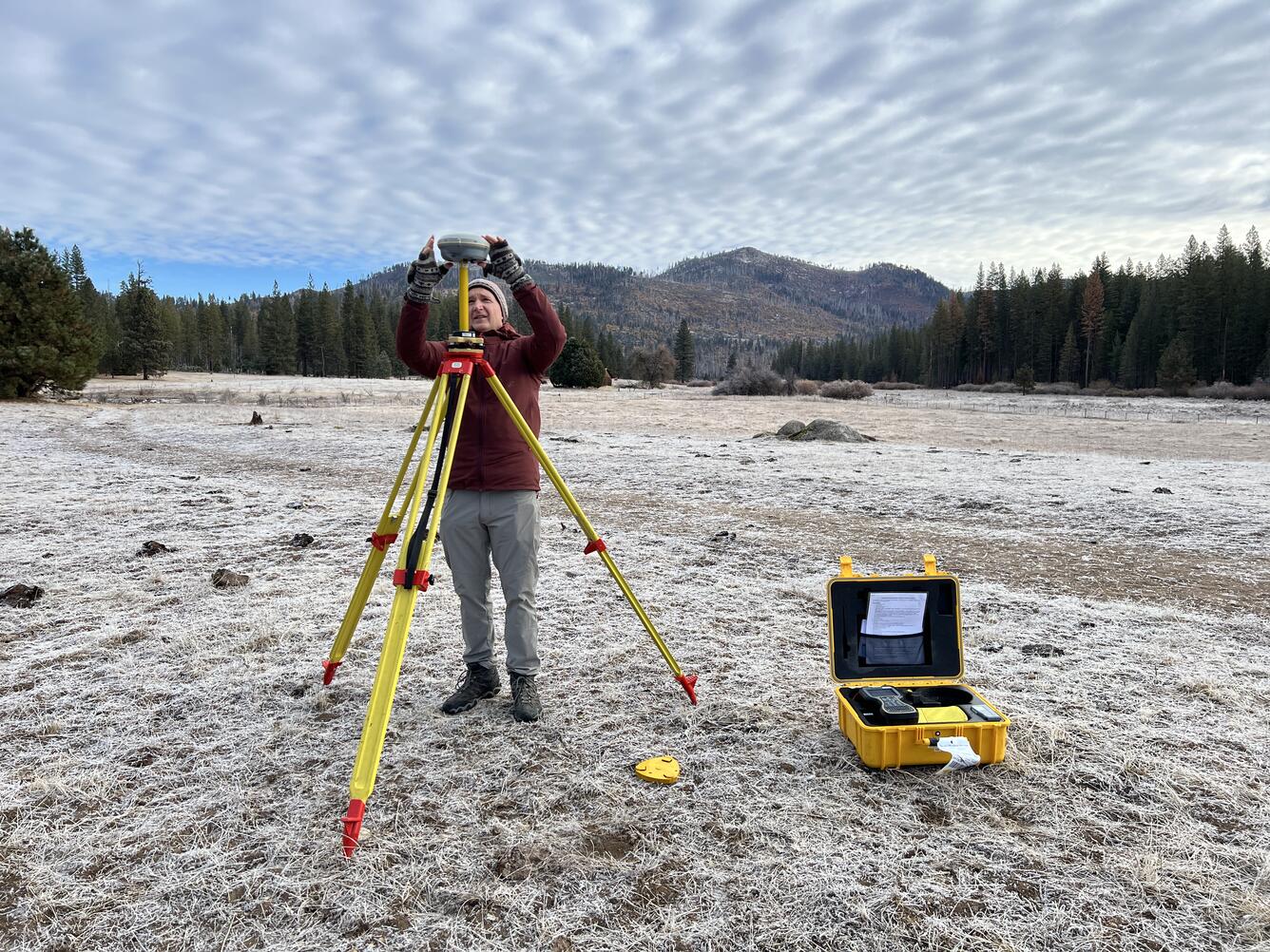 A USGS field worker adjusts a GNSS receiver on a tripod in a frost-covered Yosemite meadow.