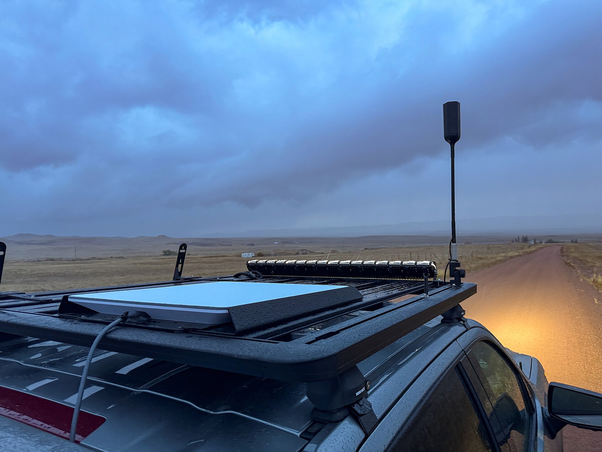 Flat-panel Starlink terminal mounted on a vehicle roof beneath an open sky, illustrating the mounting and sky-view problem for airborne installations.